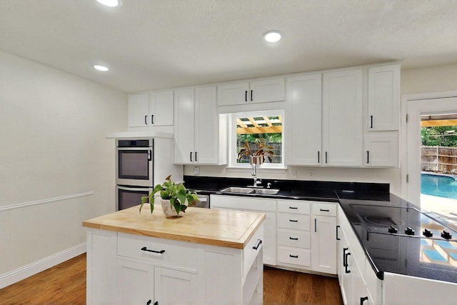 53 Devonshire Dr, Bedford, TX 76021 - kitchen with wood counters, a sink, dark wood-type flooring, stainless steel double oven, and white cabinets
