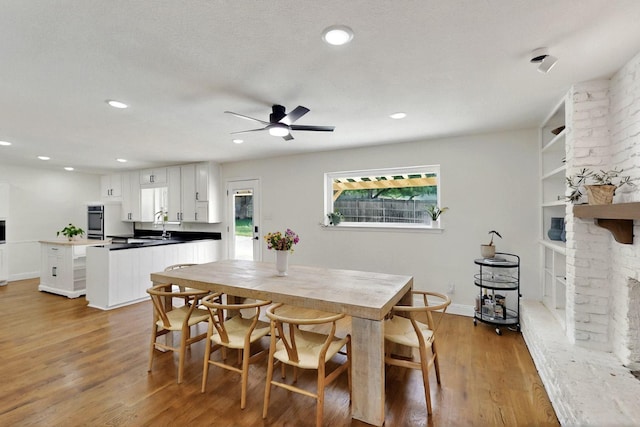53 Devonshire Dr, Bedford, TX 76021 - dining area featuring light wood finished floors, a brick fireplace, ceiling fan, recessed lighting, and baseboards