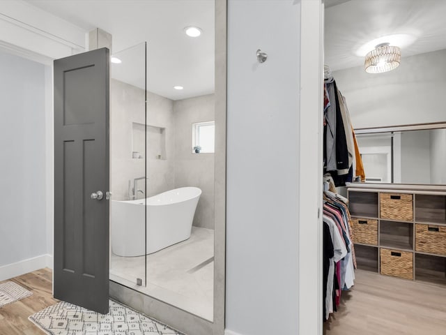 325 Beasley Rd, Combine, TX 75159 - full bathroom featuring wood finished floors, a freestanding tub, a walk in closet, and baseboards
