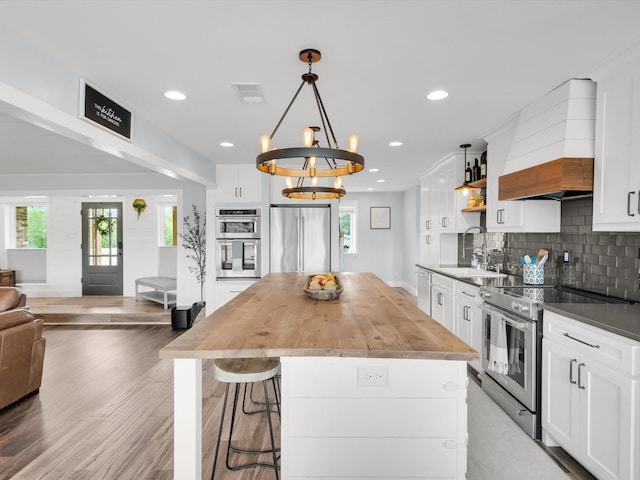 325 Beasley Rd, Combine, TX 75159 - kitchen featuring stainless steel appliances, premium range hood, recessed lighting, decorative backsplash, and a center island