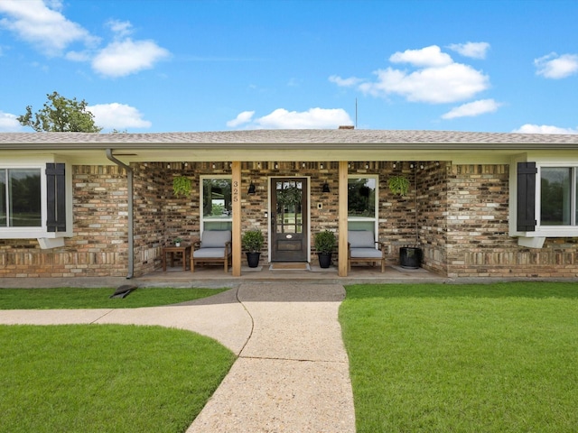 325 Beasley Rd, Combine, TX 75159 - view of exterior entry with covered porch, a lawn, brick siding, and a shingled roof
