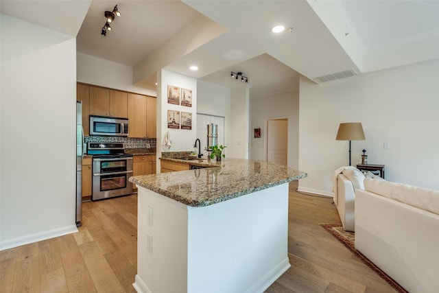 3225 Turtle Creek Blvd Unit 326, Dallas, TX 75219 - kitchen with appliances with stainless steel finishes, a sink, a peninsula, tasteful backsplash, and light wood-style flooring