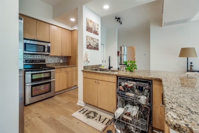 3225 Turtle Creek Blvd Unit 326, Dallas, TX 75219 - kitchen with appliances with stainless steel finishes, a sink, light wood finished floors, light stone counters, and tasteful backsplash