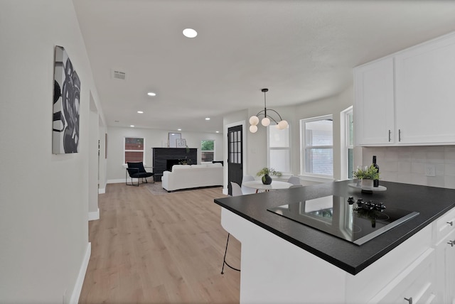 1146 Norwood Dr, Hurst, TX 76053 - kitchen featuring black electric stovetop, dark countertops, white cabinets, light wood-style floors, and a fireplace
