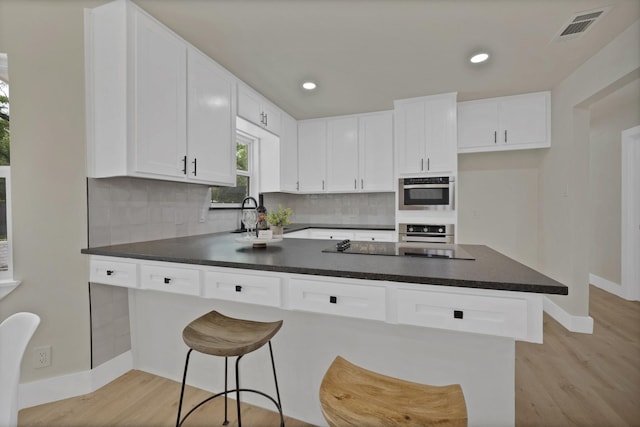 1146 Norwood Dr, Hurst, TX 76053 - kitchen featuring stainless steel oven, baseboards, dark countertops, light wood-type flooring, and recessed lighting