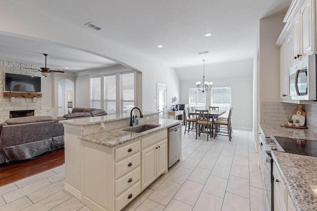 160 Melbourne Dr, Willow Park, TX 76087 - kitchen with a sink, stainless steel appliances, arched walkways, ceiling fan, and a stone fireplace