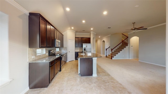 304 Eden Dr, Fate, TX 75189 - kitchen with appliances with stainless steel finishes, arched walkways, crown molding, stone counters, and a kitchen island with sink