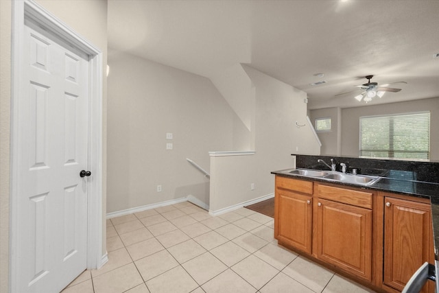 908 Glenn Crossett St, Arlington, TX 76010 - kitchen featuring a sink, a ceiling fan, brown cabinetry, light tile patterned floors, and baseboards