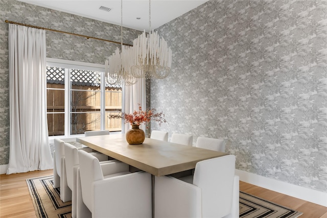 dining area featuring a chandelier, wood finished floors, wallpapered walls, and baseboards