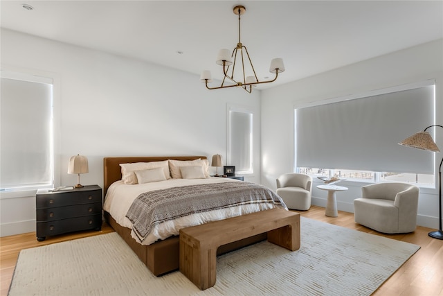 bedroom with a chandelier, wood finished floors, and baseboards