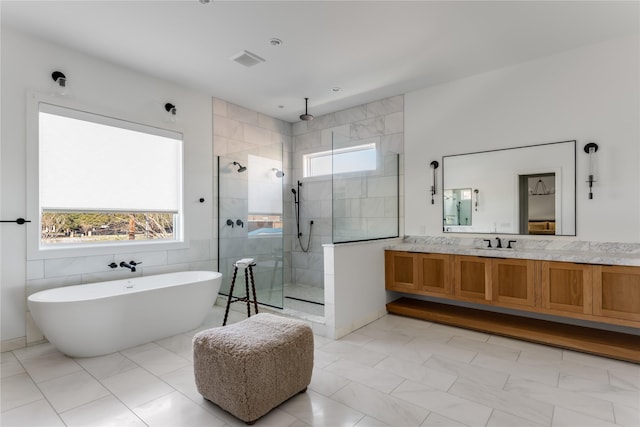 full bath featuring tiled shower, a freestanding tub, vanity, and tile walls