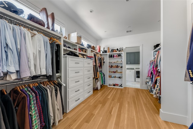 walk in closet with separate washer and dryer and light wood finished floors