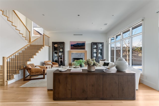 living area with stairway, light wood-style floors, and a high end fireplace