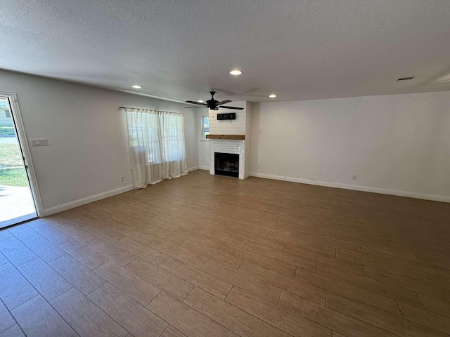2158 Morning Glory Ave, Fort Worth, TX 76111 - unfurnished living room featuring a textured ceiling, recessed lighting, a fireplace, ceiling fan, and wood finished floors