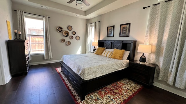 4557 El Paso Dr, Plano, TX 75024 - bedroom with baseboards, dark wood-style flooring, a tray ceiling, and ceiling fan