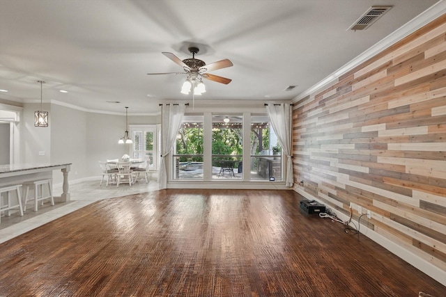 1309 Constitution Dr, Mckinney, TX 75071 - unfurnished living room with wooden walls, ceiling fan, crown molding, wood finished floors, and baseboards