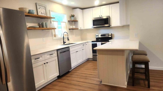 1709 Pamela Ln, Fort Worth, TX 76112 - kitchen featuring appliances with stainless steel finishes, open shelves, a kitchen breakfast bar, a peninsula, and white cabinetry