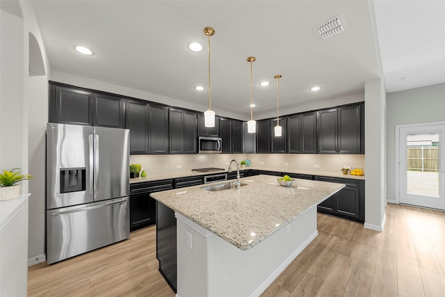 3117 Moldboard Dr, Mckinney, TX 75071 - kitchen with appliances with stainless steel finishes, a sink, light stone countertops, a kitchen island with sink, and light wood-style flooring
