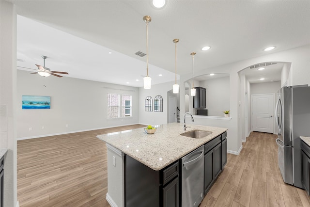 3117 Moldboard Dr, Mckinney, TX 75071 - kitchen featuring appliances with stainless steel finishes, a sink, arched walkways, light wood-type flooring, and recessed lighting