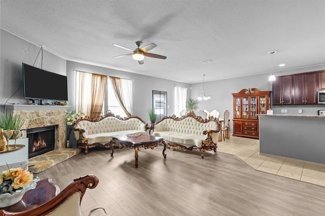 2304 Bermont Red Ln, Fort Worth, TX 76131 - living area featuring a ceiling fan, a fireplace, light wood finished floors, and a textured ceiling