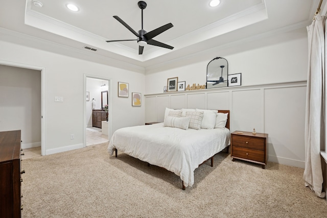 carpeted bedroom featuring a tray ceiling, ornamental molding, recessed lighting, ensuite bath, and a ceiling fan