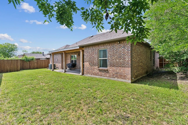 rear view of property with brick siding, a patio, cooling unit, and a shingled roof