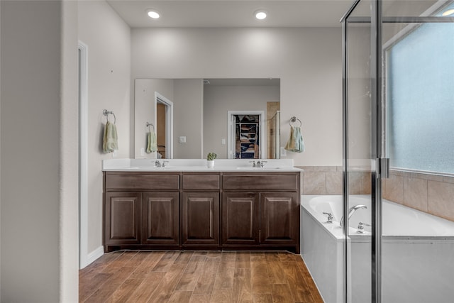 411 Skipper Ln, Azle, TX 76020 - bathroom featuring a bath, a spacious closet, double vanity, wood finished floors, and a stall shower