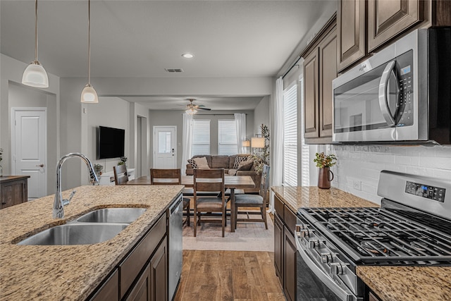411 Skipper Ln, Azle, TX 76020 - kitchen featuring appliances with stainless steel finishes, a sink, open floor plan, dark brown cabinetry, and recessed lighting