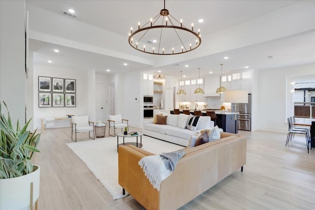 living room with light wood-style floors, a chandelier, and recessed lighting