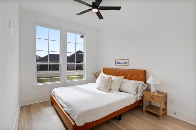 bedroom with baseboards, light wood finished floors, and ceiling fan