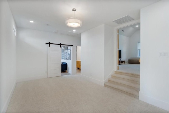 carpeted empty room featuring baseboards, attic access, recessed lighting, and a barn door