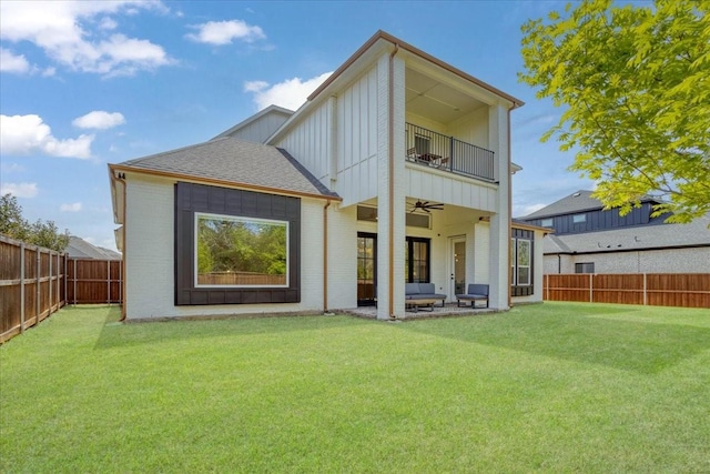 back of property with a ceiling fan, board and batten siding, a balcony, a patio area, and brick siding