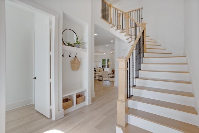 staircase with wood finished floors, a towering ceiling, and baseboards