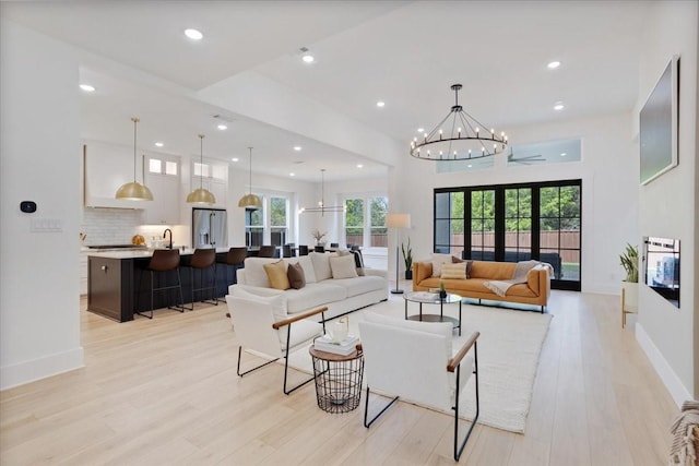 living area featuring a chandelier, light wood-type flooring, recessed lighting, and baseboards