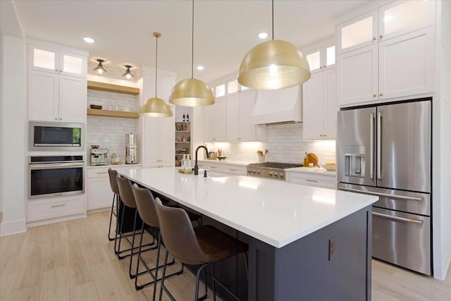 kitchen featuring stainless steel appliances, custom exhaust hood, tasteful backsplash, open shelves, and light countertops