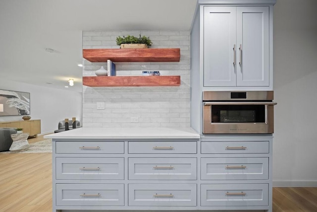 1500 W Virginia St, Mckinney, TX 75069 - kitchen with oven, wood finished floors, tasteful backsplash, open shelves, and light countertops