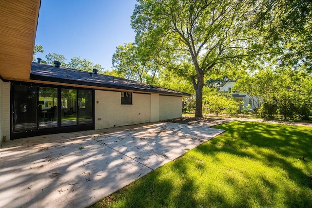 1500 W Virginia St, Mckinney, TX 75069 - view of side of property featuring a patio area, a lawn, and brick siding