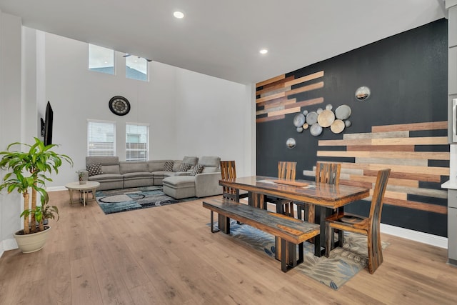 4533 Wilbarger St, Plano, TX 75024 - dining area featuring an accent wall, light wood-type flooring, recessed lighting, baseboards, and a towering ceiling