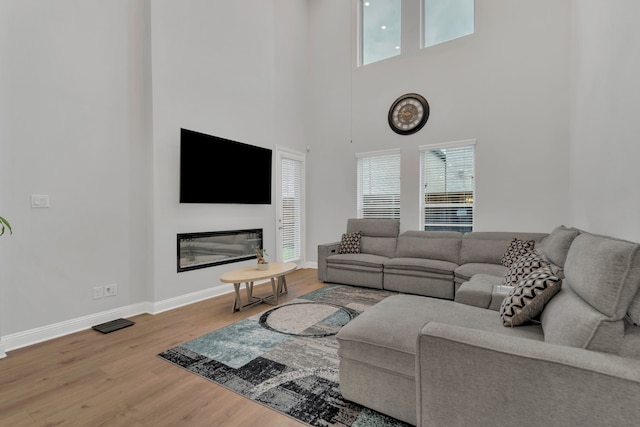 4533 Wilbarger St, Plano, TX 75024 - living area with wood finished floors, baseboards, a glass covered fireplace, and a high ceiling