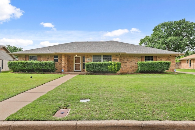 single story home featuring brick siding, a front yard, and a shingled roof
