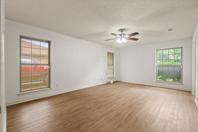 empty room with a ceiling fan, a textured ceiling, wood finished floors, and baseboards