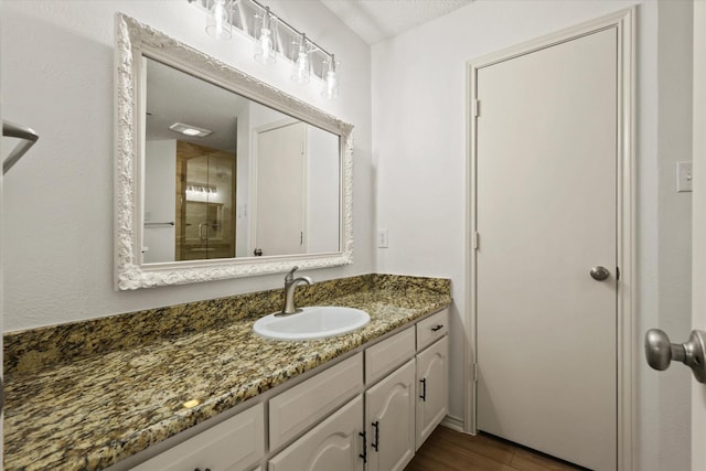 bathroom featuring vanity, a shower with door, and wood finished floors