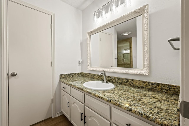 bathroom with a stall shower, vanity, and wood finished floors