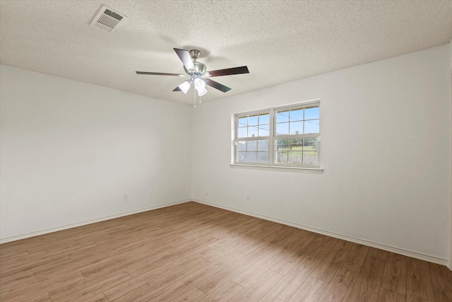 spare room with light wood-style floors, a ceiling fan, a textured ceiling, and baseboards