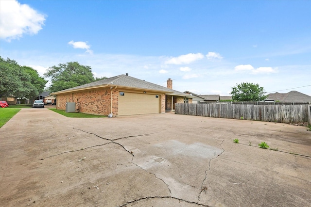 view of side of home featuring brick siding, fence, driveway, and an attached garage