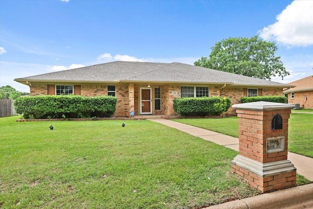 ranch-style home featuring a front yard, brick siding, and roof with shingles