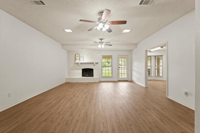 unfurnished living room featuring a ceiling fan, a textured ceiling, wood finished floors, baseboards, and a fireplace