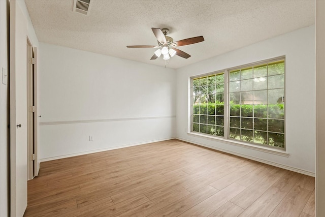 unfurnished room with wood finished floors, ceiling fan, a textured ceiling, and baseboards