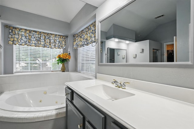 full bathroom featuring healthy amount of natural light, vaulted ceiling, a whirlpool tub, and vanity
