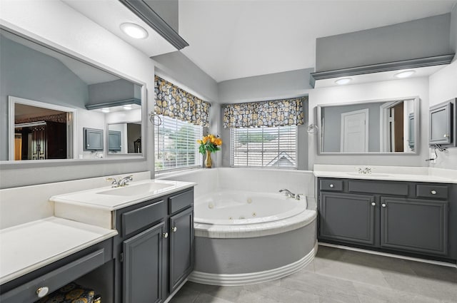 full bathroom with a jetted tub, two vanities, and vaulted ceiling